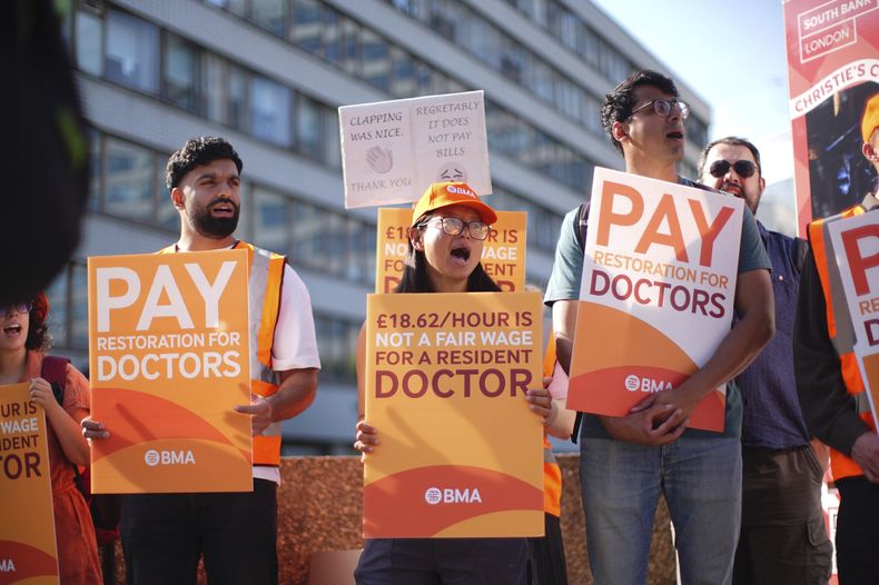 Médicos residentes y simpatizantes afuera del Hospital St. Thomas mientras inician una huelga de cinco días para pedir mejores salarios, en Londres, el viernes 25 de julio de 2025. (James Manning/PA vía AP)