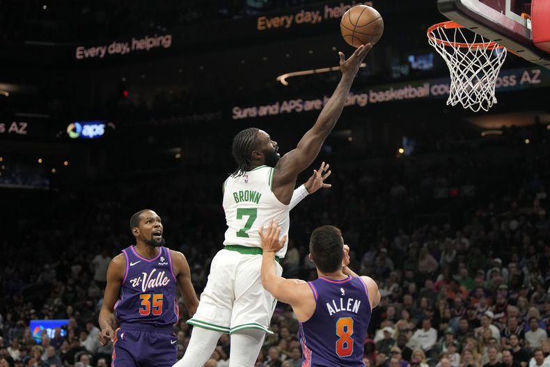 El escolta de los Celtics de Boston, Jaylen Brown (7), conduce entre el alero de los Suns de Phoenix, Kevin Durant (35), y el escolta Grayson Allen (8), durante la primera mitad del partido de baloncesto de la NBA, el sábado 9 de marzo de 2024, en Phoenix. (AP Foto/Rick Scuteri)