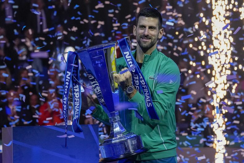 Novak Djokovic carga el trofeo de campeón de la Copa de Maestros de la ATP tras derrotar a Jannik Sinner en la final, el domingo 19 de noviembre de 2023, en Turín. (AP Foto/Antonio Calanni)
