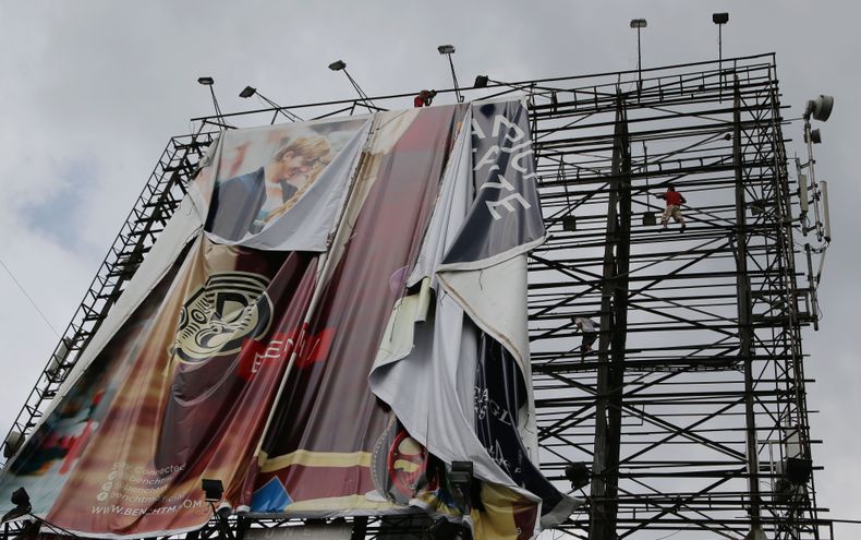 Trabajadores retiran una enorme valla publicitaria junto a una autopista como parte de los preparativos para los posibles efectos del poderoso tif&oacute;n Haiyan en Makati, al sur de Manila, Filipinas, el jueves 7 de noviembre de 2013. (Foto AP/Aaron Fav