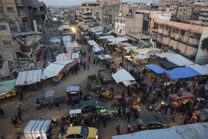 Palestinos caminan por un mercado callejero en Jan Yunis, en el centro de la Franja de Gaza, el sábado 18 de enero de 2025. (AP Foto/Jehad Alshrafi)