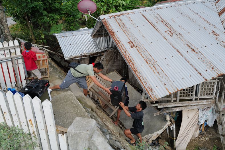 Residentes sacan objetos de una casa dañada por un sismo mientras evacúan la zona, en la localidad de Manay, en la provincia de Davao Oriental, en el sur de Filipinas, el 11 de octubre de 2025. (AP Foto/Jeoffrey Maitem)