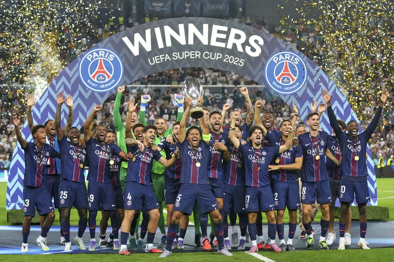 El capitán del PSG Marquinhos, centro, alza el trofeo para júbilo de sus compañeros de equipo después de ganar la Supercopa Europea en duelo entre el Paris Saint-Germain y Tottenham Hotspur, en Údine, Italia, el miércoles 13 de agosto de 2025. (AP Foto/Antonio Calanni)