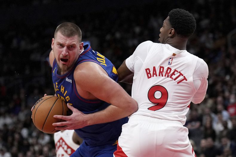 Nikola Jokic, izquierda, de los Nuggets de Denver, intenta superar a RJ Barrett (9), de los Raptors de Toronto, durante la segunda mitad del juego de baloncesto de la NBA, el lunes 28 de octubre de 2024, en Toronto. (Nathan Denette/The Canadian Press vía AP)