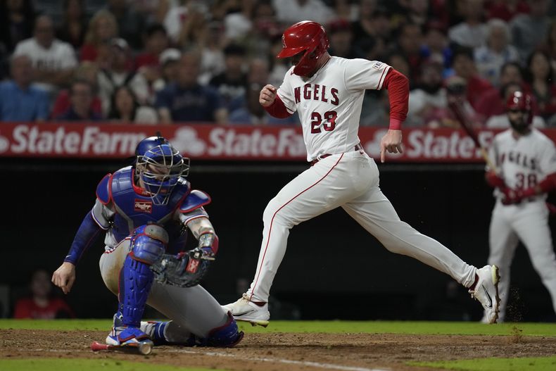 Brandon Drury, de los Angelinos de Los Ángeles, anota frente a Jonah Heim, cátcher de los Rangers de Texas, en el juego del martes 26 de septiembre de 2023 (AP Foto/Ashley Landis)