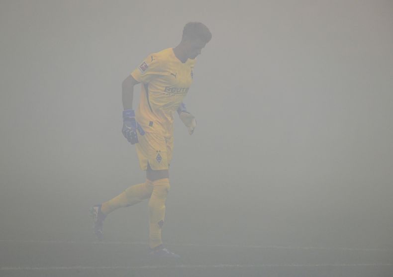 Jonas Omlin, arquero del Borussia Mönchengladbach, camina en la cancha en medio del humo despedido por una serie de bengalas, en el partido del viernes 23 de agosto de 2024, ante el Bayern Leverkusen (Mönchengladbach/dpa via AP)