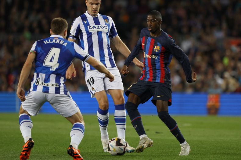 Ousmane Dembele del Barcelona pelea por el balón con Asier Illarramendi y Alexander Sorloth de la Real Sociedad en el encuentro de la liga española el sábado 20 de mayo del 2023. (AP Foto/Joan Monfort)