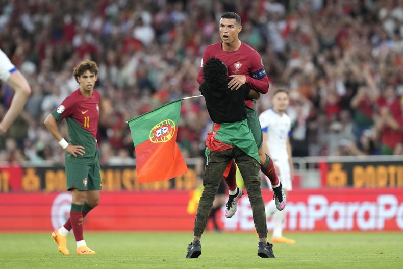 Un individuo que irrumpió en la cancha abraza al astro portugués Cristiano Ronaldo durante el partido contra Bosnia y Herzegovina por las eliminatorias de la Eurocopa, el sábado 17 de junio de 2023, en Lisboa. (AP Foto/Armando Franca)