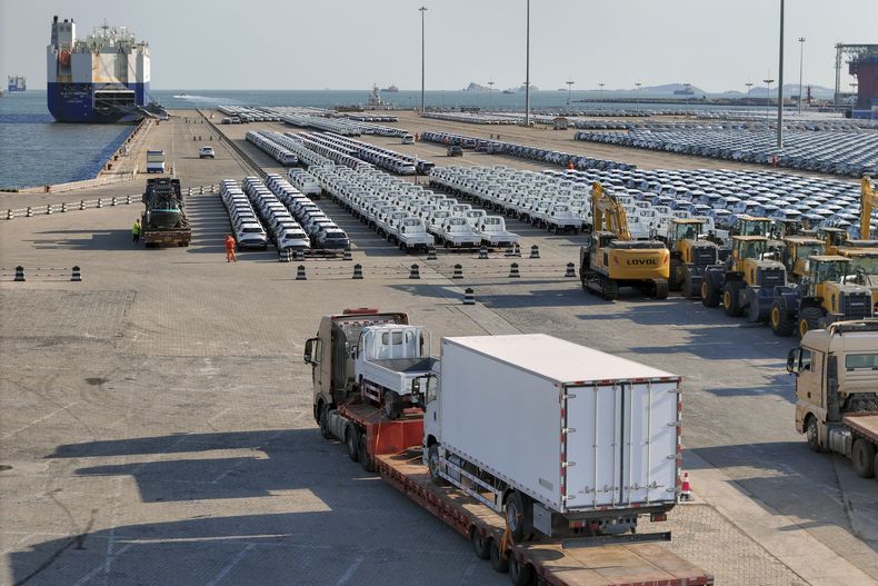ARCHIVO – Un camión cargado de vehículos avanza frente a varias filas de automóviles para exportación en un puerto de Yantai, en la provincia de Shandong, en el este de China, el 2 de enero de 2025. (Chinatopix vía AP, Archivo)