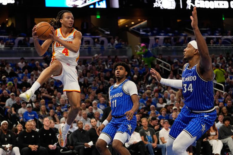 Kingston Flemings, base de los Hawks de Atlanta, envía un pase frente a Jase Richardson (11) y Wendell Carter Jr., del Magic de Orlando, el miércoles 21 de octubre de 2026 (AP Foto/John Raoux)