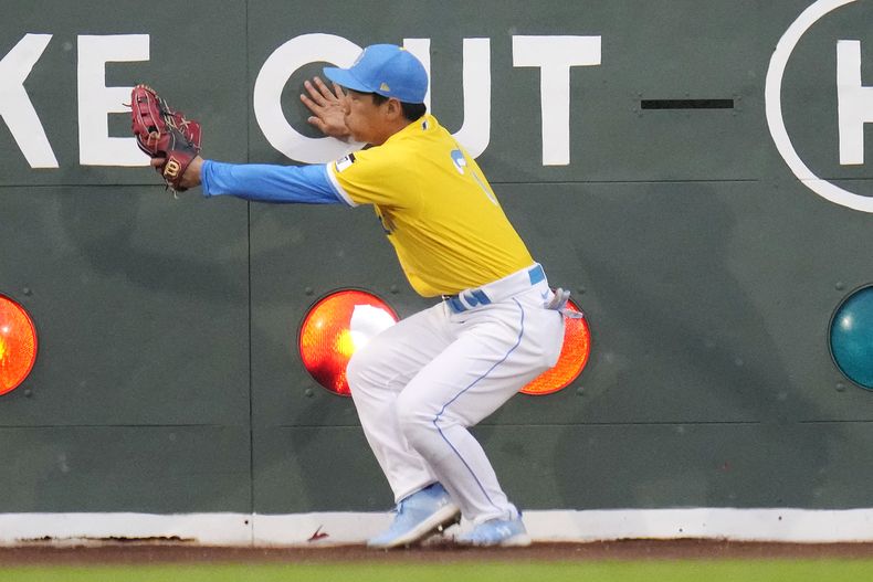 Masataka Yoshida, jardinero izquierdo de los Medias Rojas de Boston, se estrella contra la barda mientras falla una atrapada a batazo de Kyle Isbel, de los Reales de Kansas City, el miércoles 9 de agosto de 2023, en Boston. La pelota rompió uno de los focos que indican los outs en el tablero y se quedó en el hueco, por lo que se marcó doble por regla. (AP Foto/Charles Krupa)