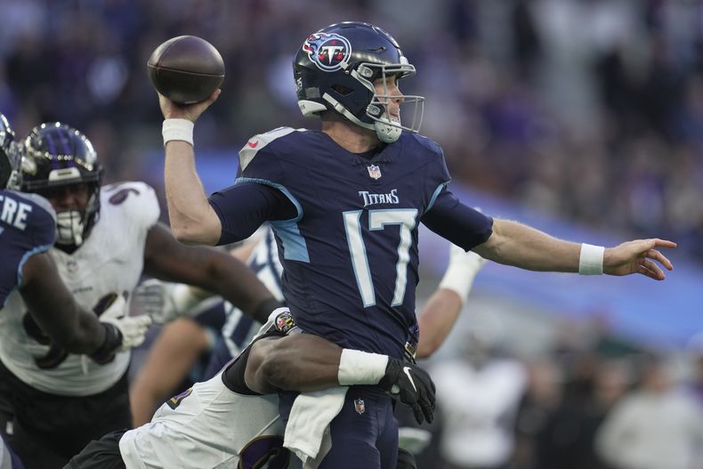 Ryan Tannehill (17), quarterback de los Titans de Tennessee, busca lanzar el balón mientras es presionado por un defensivo de los Ravens de Baltimore, en la segunda mitad del partido de la NFL, el domingo 15 de octubre de 2023, en el estadio del Tottenham Hotspur, en Londres. (AP Foto/Kin Cheung)