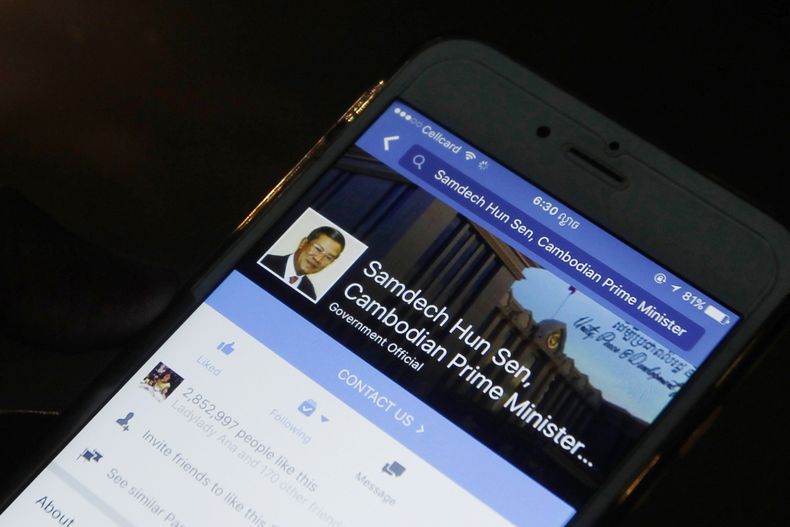 ARCHIVO - Un hombre mira la página de Facebook del primer ministro camboyano Hun Sen en su teléfono celular en Phnom Penh, Camboya, 1 de marzo de 2016. (AP Foto/Heng Sinith, File)