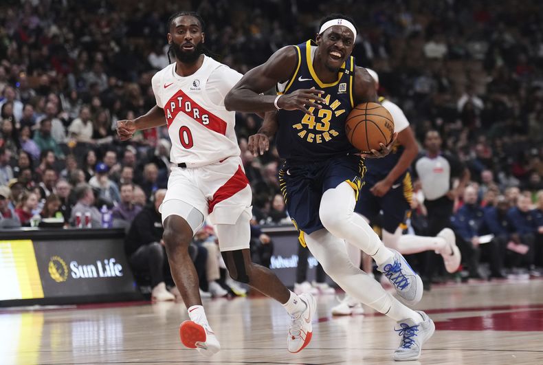 El alero de los Pacers de Indiana Pascal Siakam avanza con el balón a la canasta superando al base de los Raptors de Toronto Javon Freeman-Liberty en el encuentro del martes 9 de abril del 2024. (Nathan Denette/The Canadian Press via AP)