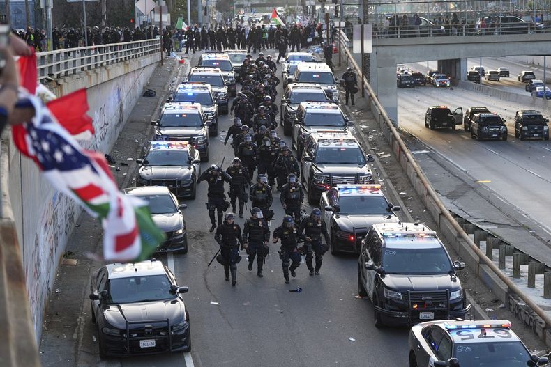 Un grupo de agentes policiales avanza por una rampa de la vía rápida 101 cerca del Centro de Detención Metropolitano, el domingo 8 de junio de 2025, en el centro de Los Ángeles. (AP Foto/Jae C. Hong)
