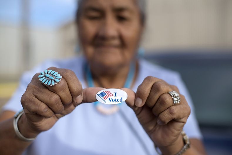 Mildred James, de Sanders, Arizona, muestra su calcomanía de Yo voté mientras espera que se revelen los resultados de las elecciones primarias presidenciales de la Nación Navajo en Window Rock, Arizona, el 28 de agosto de 2018. (AP Foto/Cayla Nimmo, Archivo)