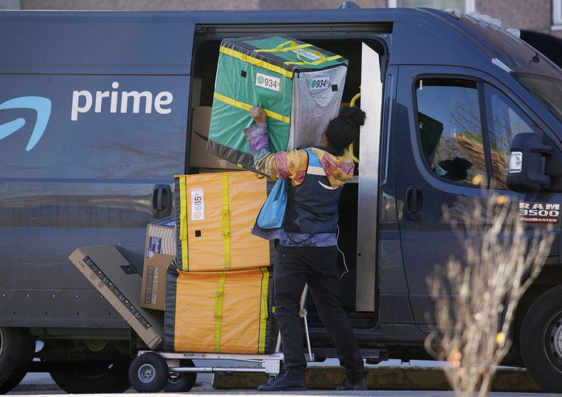 Una persona que entrega mercancía de Amazon Prime acomoda paquetes al hacer una parada en un edificio de apartamentos, el martes 28 de noviembre de 2023, en Denver. (AP Foto/David Zalubowski)