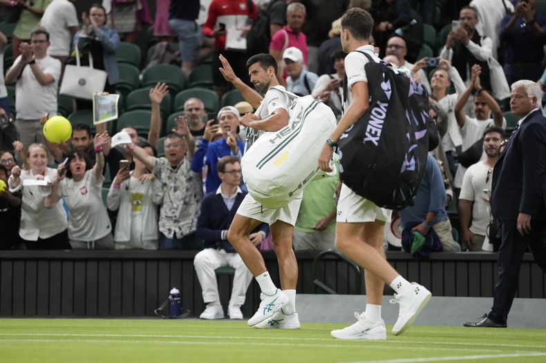 El serbio Novak Djokovic y el polaco Hubert Hurkacz abandonan la cancha luego de que su encuentro fuera suspendido debido a lo tarde que se jugaba en el campeonato de tenis de Wimbledon en Londes. Domingo 9 de julio de 2023. (AP Foto/Kirsty Wigglesworth)