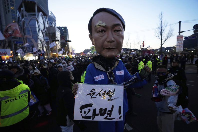 Un manifestante con una máscara del presidente surcoreano Yoon Suk Yeol, quien se encuentra en proceso de juicio político, durante una manifestación para exigir la renuncia de Yoon, el sábado 29 de marzo de 2025, en Seúl, Corea del Sur. La pancarta dice: Destituyan a Yoon Suk Yeol. (AP Foto/Ahn Young-joon)