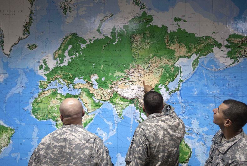 ARCHIVO – Un grupo de soldados miran un mapa mundial mientras esperan para abordar un vuelo en Manas, Kirguistán, para volver a casa tras ser desplegados en Afganistán, el jueves 11 de agosto de 2011. (AP Foto/David Goldman, Archivo)