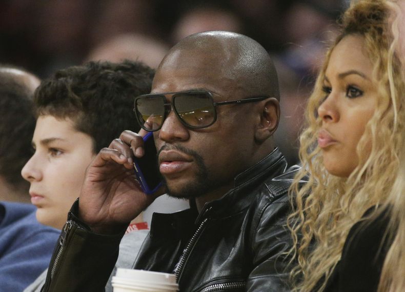 El boxeador Floyd Mayweather habla por tel&eacute;fono mientras presencia un partido entre los Lakers de Los &Aacute;ngeles y los Kings de Sacramento, el martes 9 de diciembre de 2014 (AP Foto/Jae C. Hong)