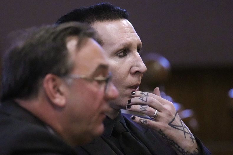 Marilyn Manson, cuyo nombre verdadero es Brian Hugh Warner, derecha, con su abogado Kent Barker durante una audiencia en la Corte Superior de Belknap, el lunes 18 de septiembre de 2023, en Laconia, Nueva Hampshire. Marilyn Manson fue sentenciado a 20 horas de servicio comunitario y una multa el lunes por sonarse la nariz sobre una camarógrafa en un concierto de 2019 en Nueva Hampshire. (Foto AP/Charles Krupa)