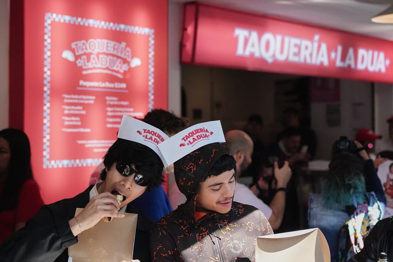 Clientes comen tacos en la apertura la taquería La Dua de la estrella de la música, un restaurante emergente para sus fans en la Ciudad de México, el lunes 1 de diciembre de 2025. (Foto AP/Eduardo Verdugo)