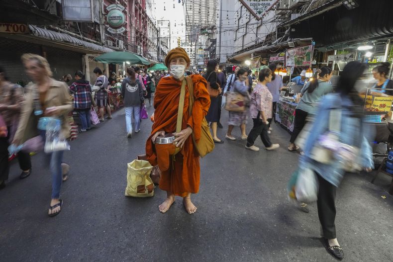 Un monje budista, con un gorro de invierno, espera recibir ofrendas en Bangkok, Tailandia, el 16 de enero de 2025. (AP Foto/Sakchai Lalit)