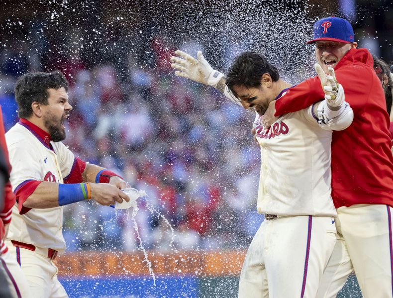 Nick Castellanos, de los Filis de Filadelfia, es empapado por su compañero Kyle Schwarber, tras conectar el hit decisivo en el encuentro del sábado 13 de abril de 2024, ante los Piratas de Pittsburgh (AP Foto/Laurence Kesterson)