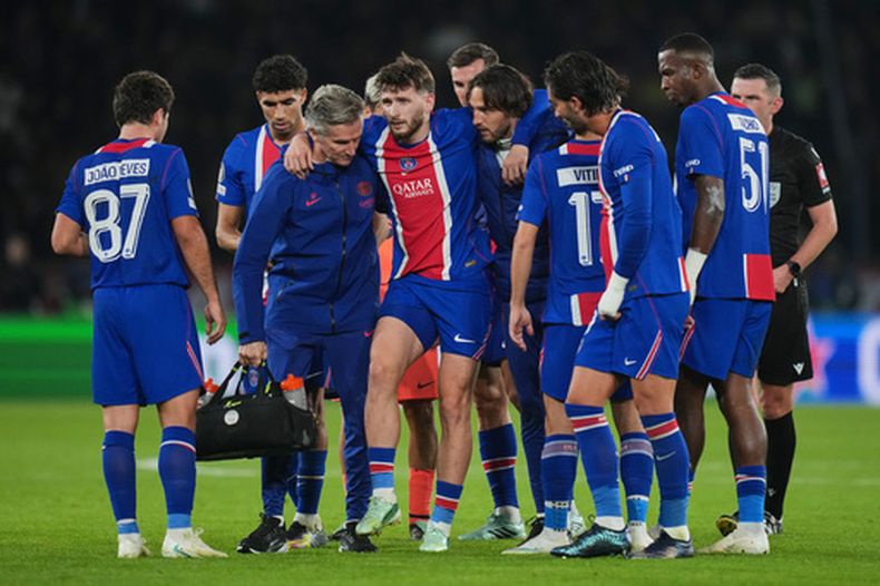Khvicha Kvaratskhelia (centro) del Paris Saint-Germain recibe asistencia tras lesionarse durante el partido contra el Barcelona por la Liga de Campeones, el martes 20 de octubre de 2026, en París. (AP Foto/Thibault Camus)