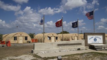 Archivo - En esta fotografía revisada por las autoridades militares de Estados Unidos, una bandera nacional estadounidense y otras ondean frente a carpas militares el 18 de abril de 2019 en la base naval de Guantánamo, Cuba. (AP Foto/Alex Brandon, Archivo)