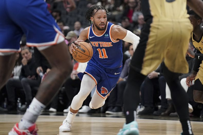 El armador de los Knicks de Nueva York Jalen Brunson (11) conduce hacia la defensa de los Raptors de Toronto en la segunda mitad del juego de NBA en Toronto, el viernes 1 de diciembre de 2023. (Arlyn McAdorey/The Canadian Press via AP)