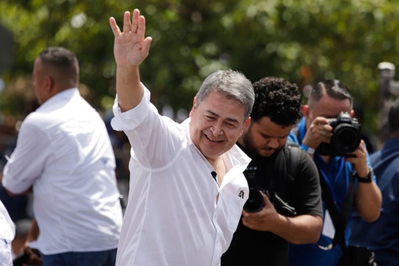 El expresidente hondureño Juan Orlando Hernández saluda con la mano tras su llegada al aeropuerto de Toncontin, en Tegucigalpa (Honduras), el domingo 26 de julio de 2026. (Foto AP/Fernando Destephen)