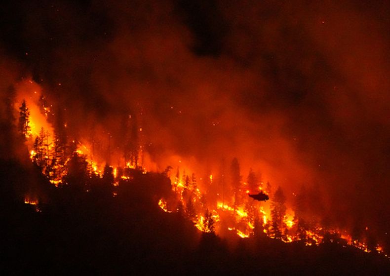 ARCHIVO - Un helicóptero que realiza operaciones nocturnas se prepara para arrojar agua sobre el incendio forestal de Quilpituk Creek, que arde en la orilla occidental del lago Okanagan, el 3 de agosto de 2026, cerca de Fintry, Columbia Británica, Canadá. (Darryl Dyck/The Canadian Press vía AP, archivo)