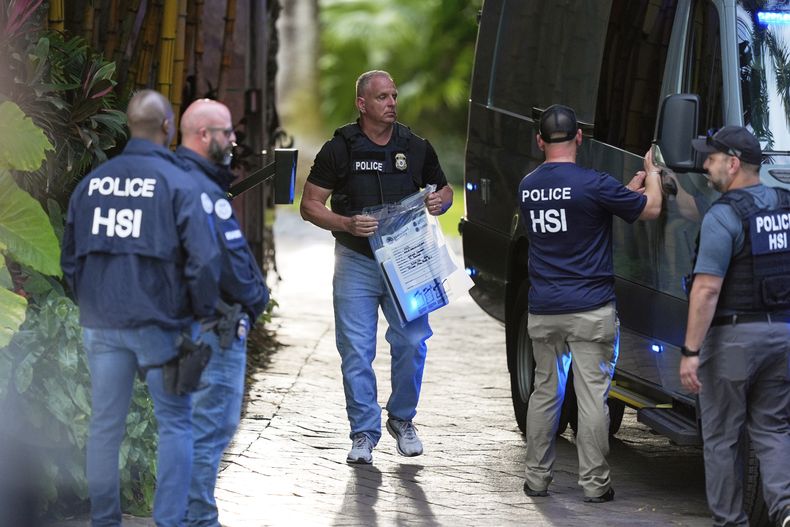 ARCHIVO - Un agente del orden lleva una bolsa de pruebas a una camioneta mientras agentes federales se encuentran en la entrada de una propiedad perteneciente al rapero Sean Diddy Combs, el 25 de marzo de 2024, en Star Island en Miami Beach, Florida. (Foto AP/Rebecca Blackwell, archivo)