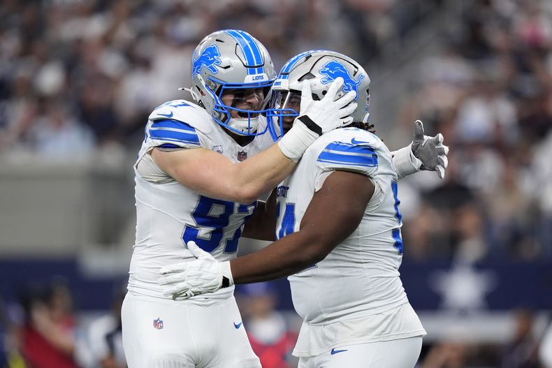 Aidan Hutchinson (97), de los Lions de Detroit, felicita a Alim McNeill, después de que éste capturara detrás de la línea a Dak Prescott (4), quarterback de los Cowboys de Dallas, en la primera mitad del juego de la NFL en Arlington, Texas, el domingo 13 de octubre de 2024, en Arlington, Texas. (AP Photo/LM Otero)