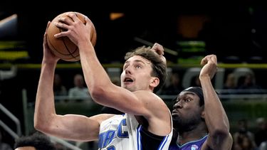 Franz Wagner (22), del Magic de Orlando, se alista para encestar frente a Mark Williams, de los Hornets de Charlotte, derecha, durante la primera mitad del juego de baloncesto de la NBA, el domingo 26 de noviembre de 2023, en Orlando, Florida. (AP Foto/John Raoux)