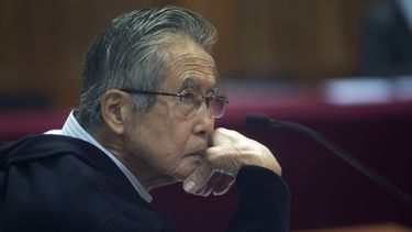 ARCHIVO - El encarcelado expresidente Alberto Fujimori, fotografiado a través de una ventana de vidrio, asiste a su juicio en una base policial en las afueras de Lima, Perú, el 28 de junio de 2016. Fujimori cumple una condena de 25 años de prisión por asesinatos cometidos durante su mandato. (Foto AP/Martín Mejía, Archivo)