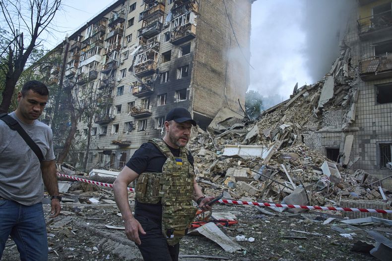 El ministro del Interior de Ucrania, Ihor Klymenko, derecha, recorre el sitio donde cayó un misil que destruyó un edificio residencial durante un ataque aéreo masivo con drones y misiles de Rusia en Kiev, Ucrania, el martes 17 de junio de 2025. (AP Foto/Efrem Lukatsky)