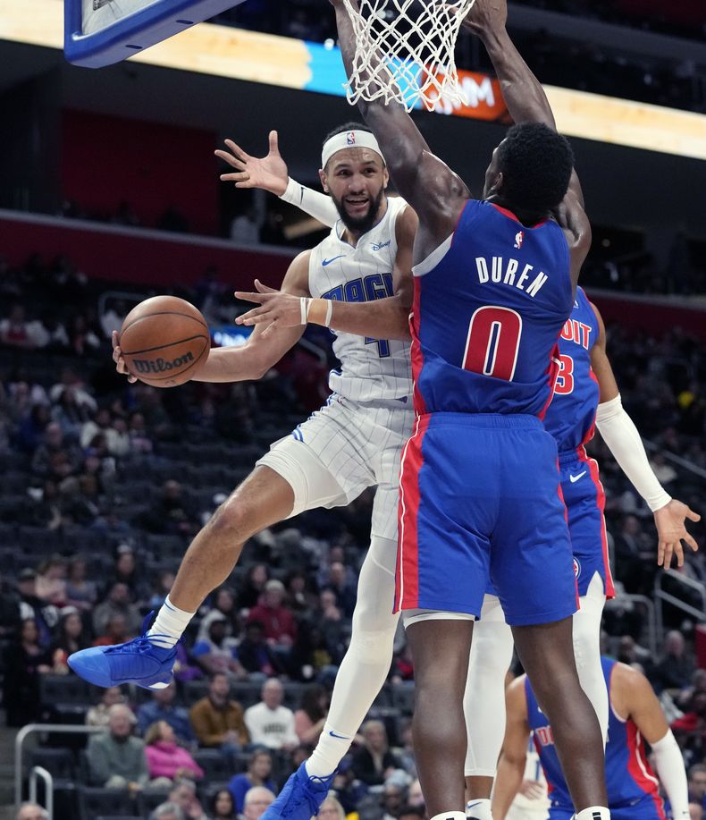 El escolta del Magic de Orlando, Jalen Suggs (4), pasa el balón mientras el pívot de los Pistons de Detroit, Jalen Duren (0), defiende durante la segunda mitad deL partido de baloncesto de la NBA, el sábado 24 de febrero de 2024, en Detroit. (AP Foto/Carlos Osorio)