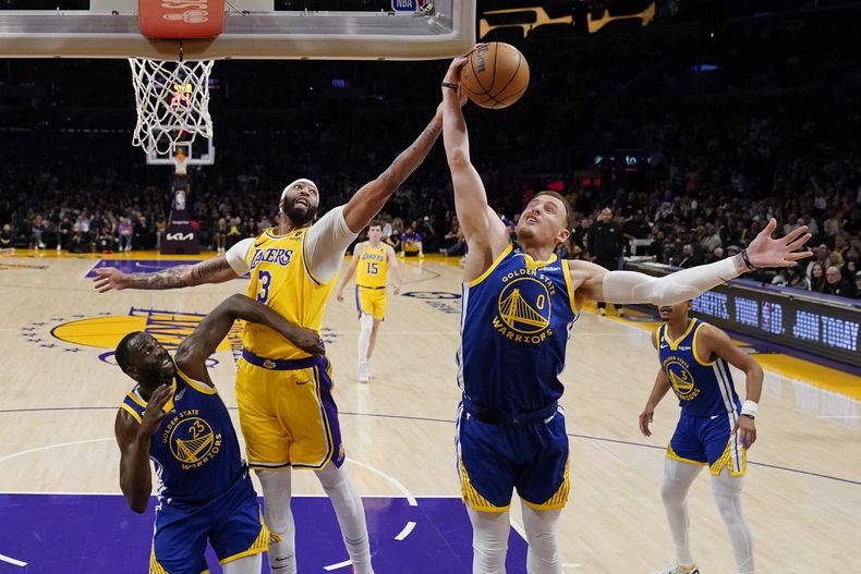 El alero de los Lakers de Los Ángeles Anthony Davis va por el rebote frente a Donte DiVincenzo y Draymond Green de los Warriors de Golden State en el juego 6 de la serie de semifinales de la Conferencia Oeste el viernes 12 de mayo del 2023. (AP Foto/Ashley Landis)