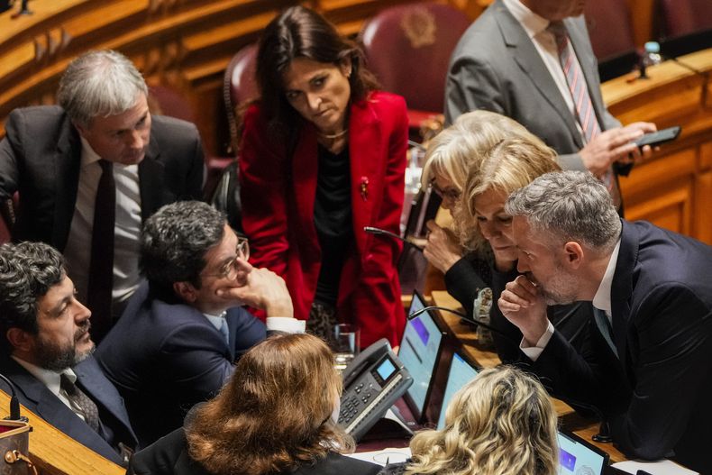 El secretario general del Partido Socialista Portugués, Pedro Nuno Santos, en primer plano y a la derecha, habla con miembros del Parlamento durante una pausa en un debate previo a una moción de confianza sobre el primer ministro portugués, Luis Montenegro, en el Parlamento, en Lisboa, Portugal, el martes 11 de marzo de 2025. (AP Foto/Armando Franca)