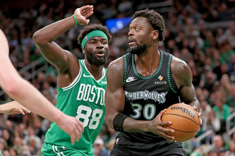 El alero de los Timberwolves de Minnesota, Julius Randle (30), defiende el balón ante el pívot de los Celtics de Boston, Neemias Queta (88), durante la primera mitad de un juego de baloncesto de la NBA, el domingo 22 de marzo de 2026, en Boston. (Foto AP/Mark Stockwell)