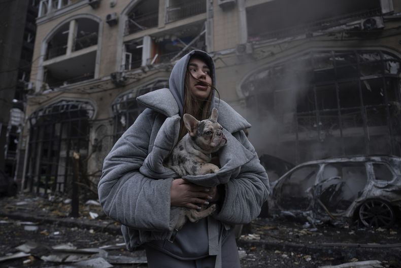 Ivanna, calienta a su perro frente a un coche en llamas destruido tras un reciente ataque ruso en Kiev, Ucrania, viernes 20 de diciembre de 2024. (Foto AP/Alex Babenko)