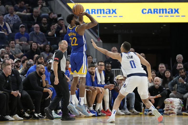 Andrew Wiggins, de los Warriors de Golden State, dispara desde la distancia de tres puntos ante Dante Exum, de los Mavericks de Dallas, el martes 2 de abril de 2024 (AP Foto/Jeff Chiu)