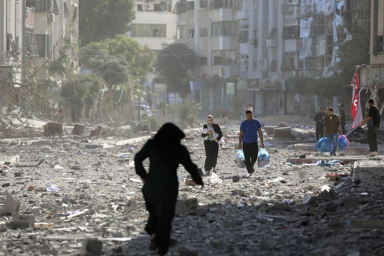 Varios palestinos salen de sus viviendas tras un bombardeo israelí, el lunes 30 de octubre de 2023, en Ciudad de Gaza. (AP Foto/Abed Khaled)