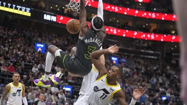 El alero de los Timberwolves de Minnesota, Jaden McDaniels (3), clava contra el escolta del Jazz de Utah, Kris Dunn (11), durante la segunda mitad del partido de baloncesto de la NBA, el sábado 16 de marzo de 2024, en Salt Lake City. (AP Foto/Rick Bowmer)