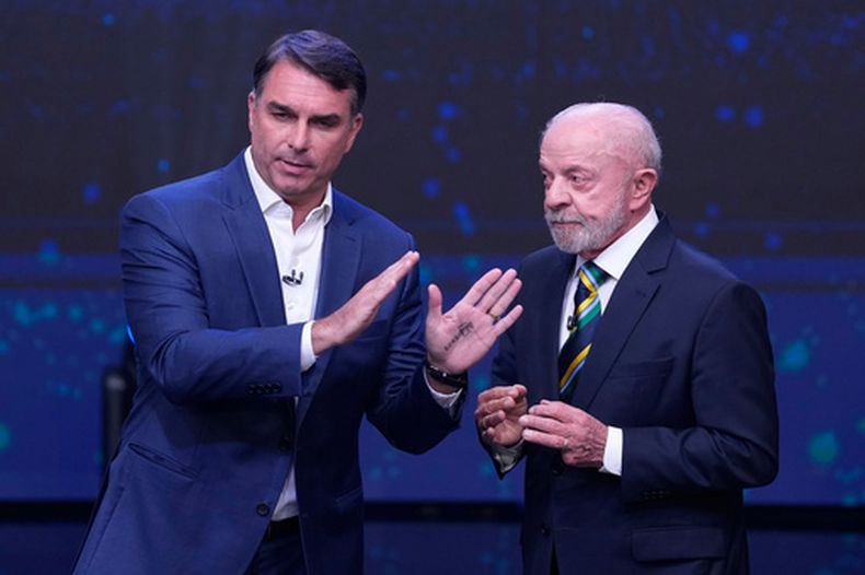 El candidato presidencial de oposición, el senador Flávio Bolsonaro, izquierda, levanta las manos mientras el presidente de Brasil, Luíz Inácio Lula da Silva, que se postula para la reelección, mira en un debate presidencial televisado, a una semana de la segunda vuelta electoral, en Sao Paulo, Brasil, el domingo 18 de octubre de 2026. (AP Foto/Andre Penner)