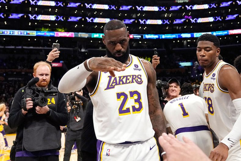 ARCHIVO - Foto del 2 de marzo del 2024, el alero de los Lakers de Los Ángeles LeBron Hames saluda al anunciador Lawrence Tanter antes del encuentro ante los Nuggets de Denver. (AP Foto/Mark J. Terrill, Archivo)