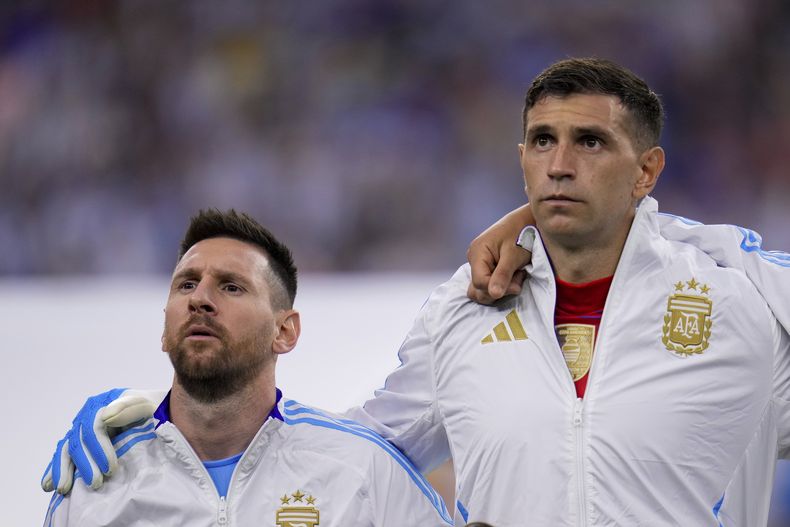 El delantero argentino Lionel Messi (izquierda) y el arquero Emiliano Martínez durante la ceremonia de himnos previo al partido contra Ecuador por los cuartos de final de la Copa América, el jueves 4 de julio de 2024, en Houston. (AP Foto/Julio Cortez)